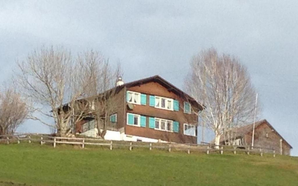 une grande maison au sommet d'une colline herbeuse dans l'établissement Neuer Sigerst, Haus, à Wildhaus