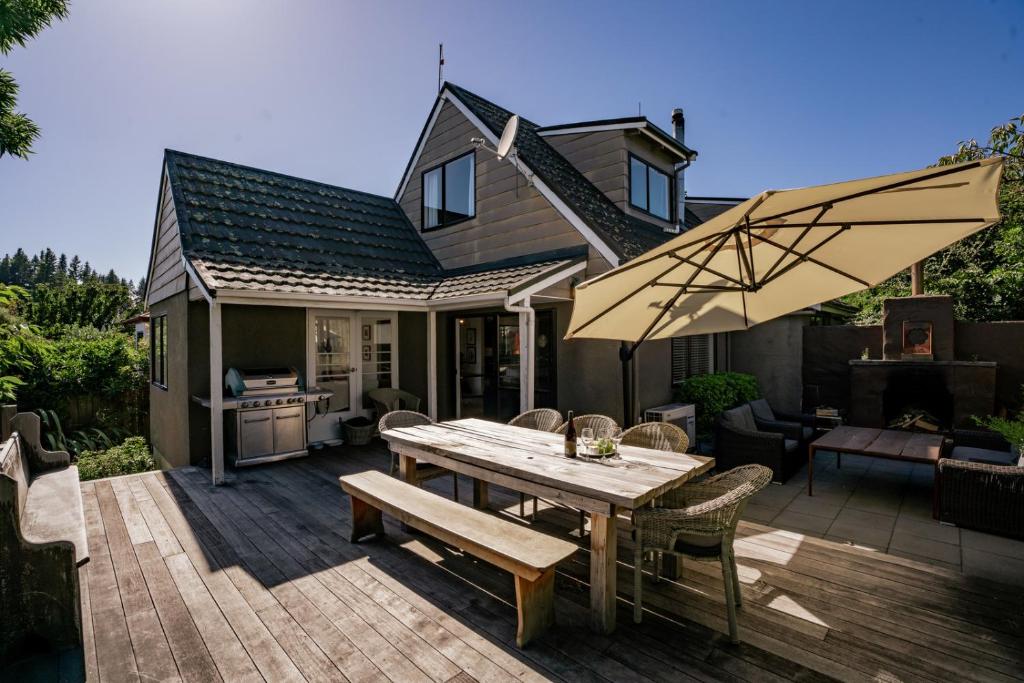 Un patio con una mesa de madera y una sombrilla. en Kings Drive - Wanaka Holiday Home, en Wanaka