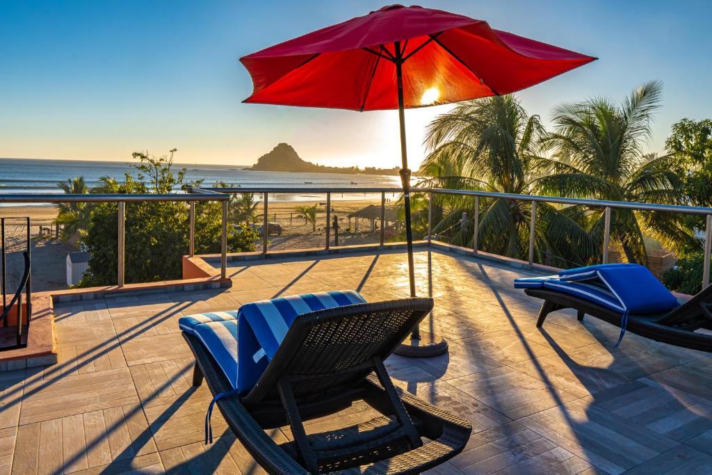 um deque com cadeiras e um guarda-sol e a praia em Casa Belen - Beautiful Beach View Home on Stone Island em Isla La Piedra