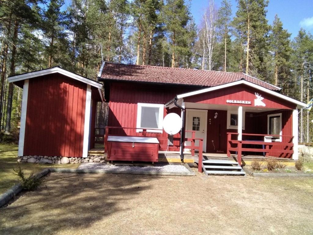 una cabaña roja en el bosque con la puerta abierta en Gepflegtes Ferienhaus mit eigenem Saunahaus, 