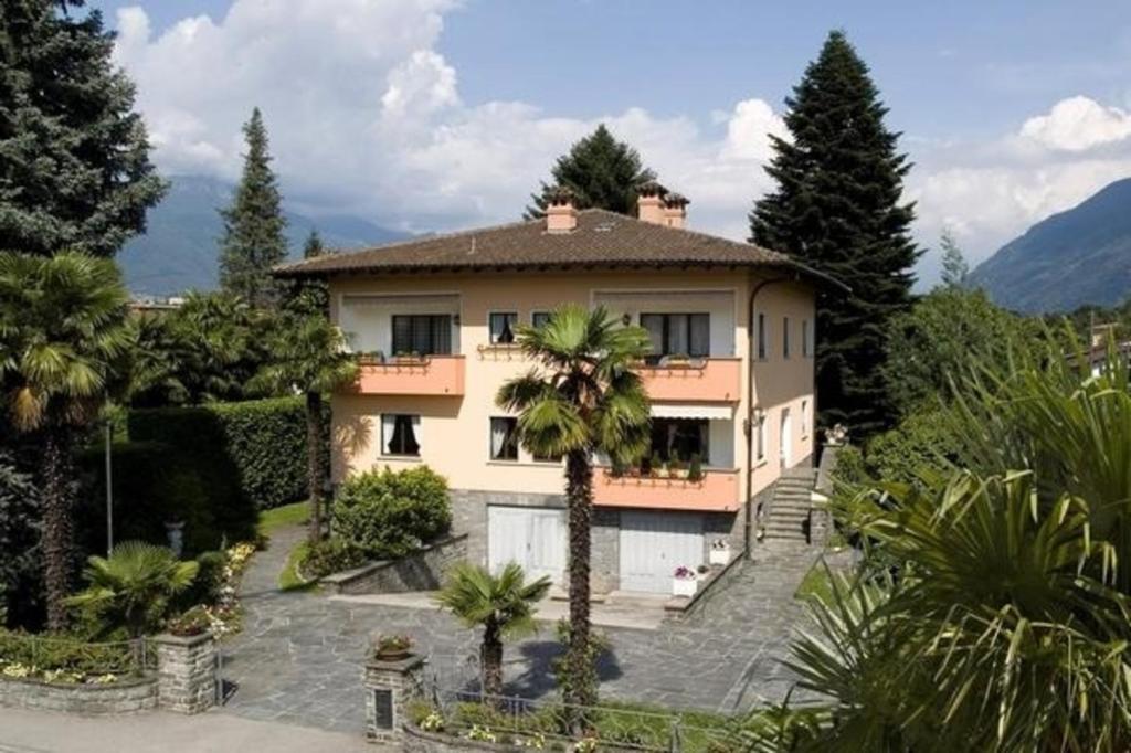 een groot huis met een palmboom ervoor bij Casa Thuja in Ascona