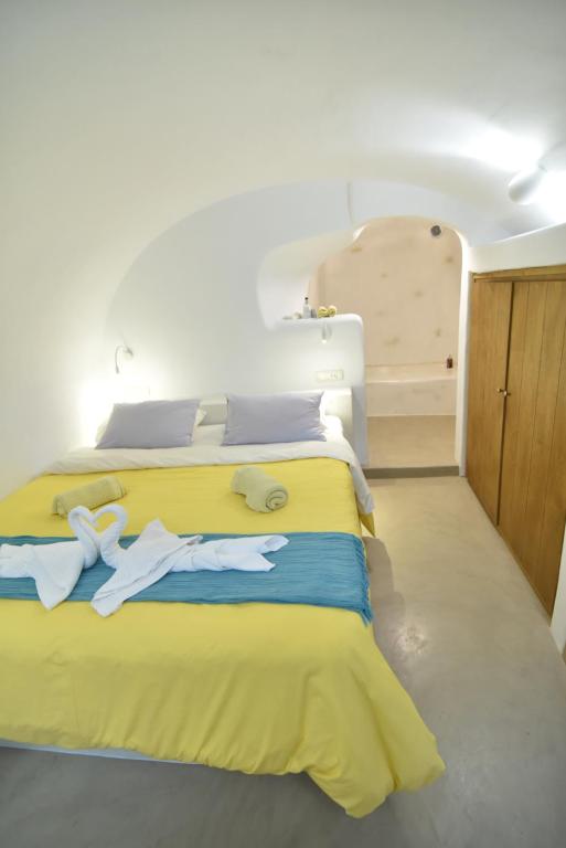 a bedroom with a yellow bed with towels on it at Maria Paradeiso Resorts in Imerovigli