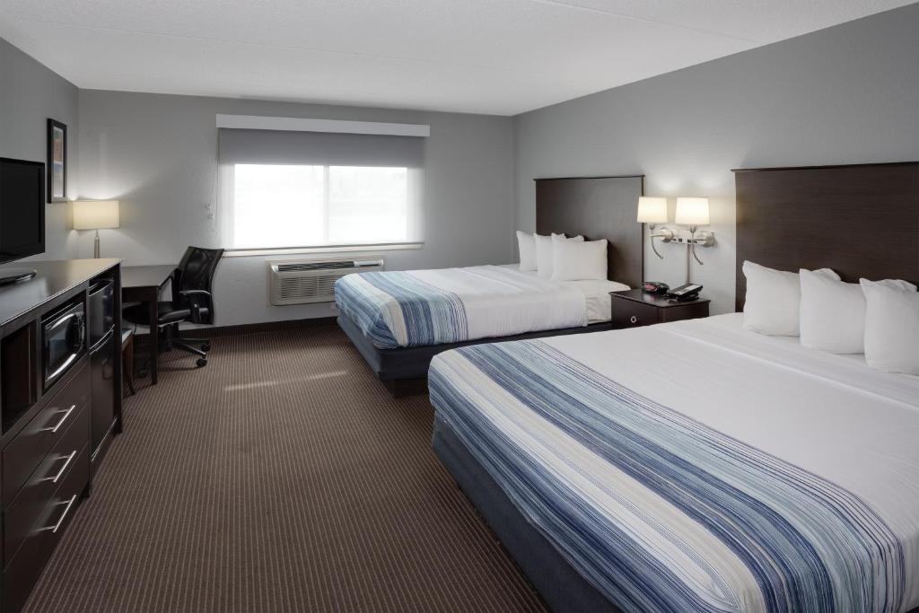 a hotel room with two beds and a flat screen tv at AmericInn by Wyndham Plover Stevens Point in Plover