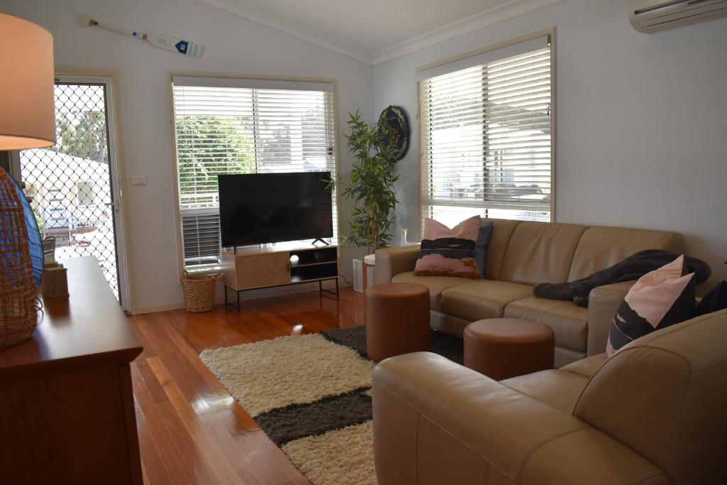 a living room with a couch and a flat screen tv at Discover St Georges Basin in St Georges Basin