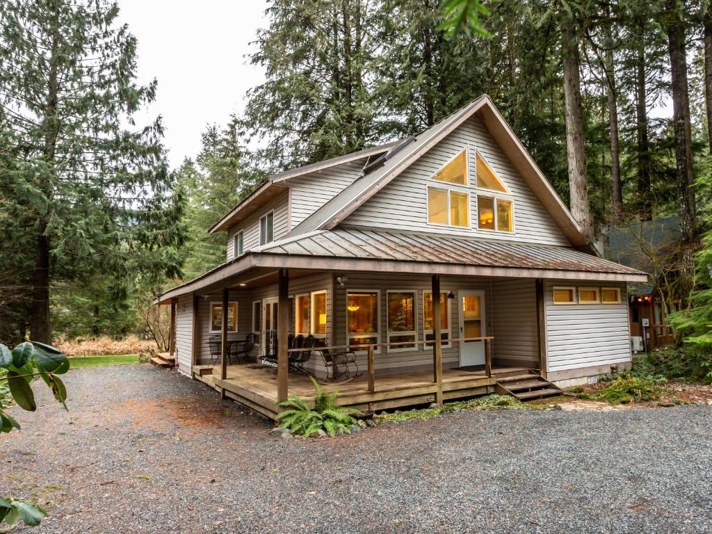 une petite maison avec une grande véranda dans les bois dans l'établissement Naturbyn Cabin, à Glacier