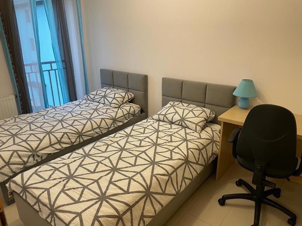 a bedroom with two beds and a desk and a chair at Apartament Solano przy plaży in Darlowko