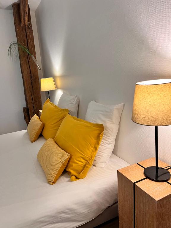 een bed met gele kussens en een tafel met een lamp bij Le domaine de Marie in Port-sur-Saône