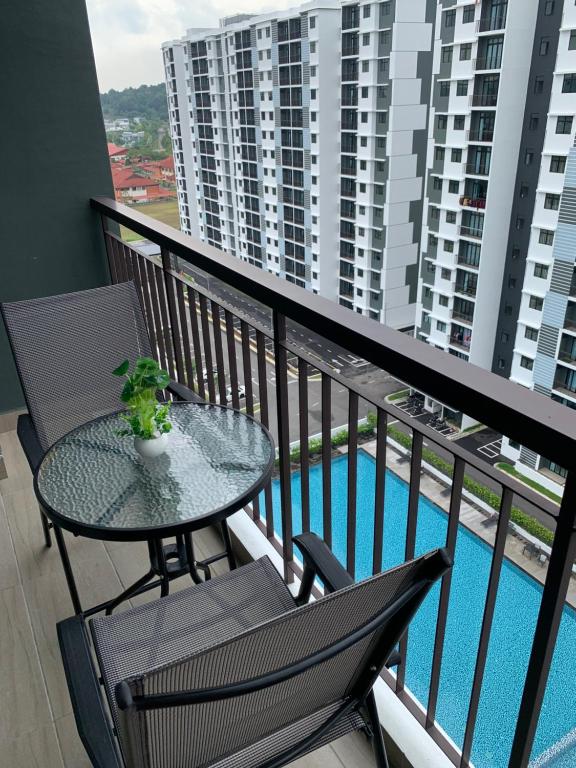 デサルにあるDesaru Utama Apartment with Swimming Pool View, Karaoke, FREE WIFI, Netflix, near to Car Parkのプール付きのバルコニー(テーブル、椅子付)
