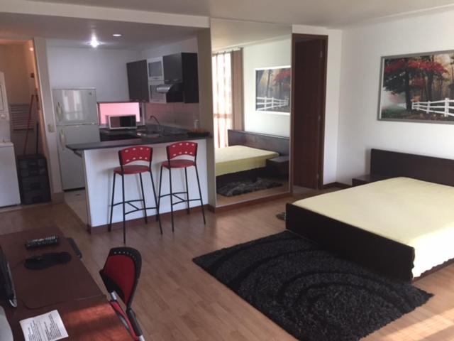 1 dormitorio con 1 cama y cocina con taburetes en Exclusive Furnished Apartment 6, en Manizales