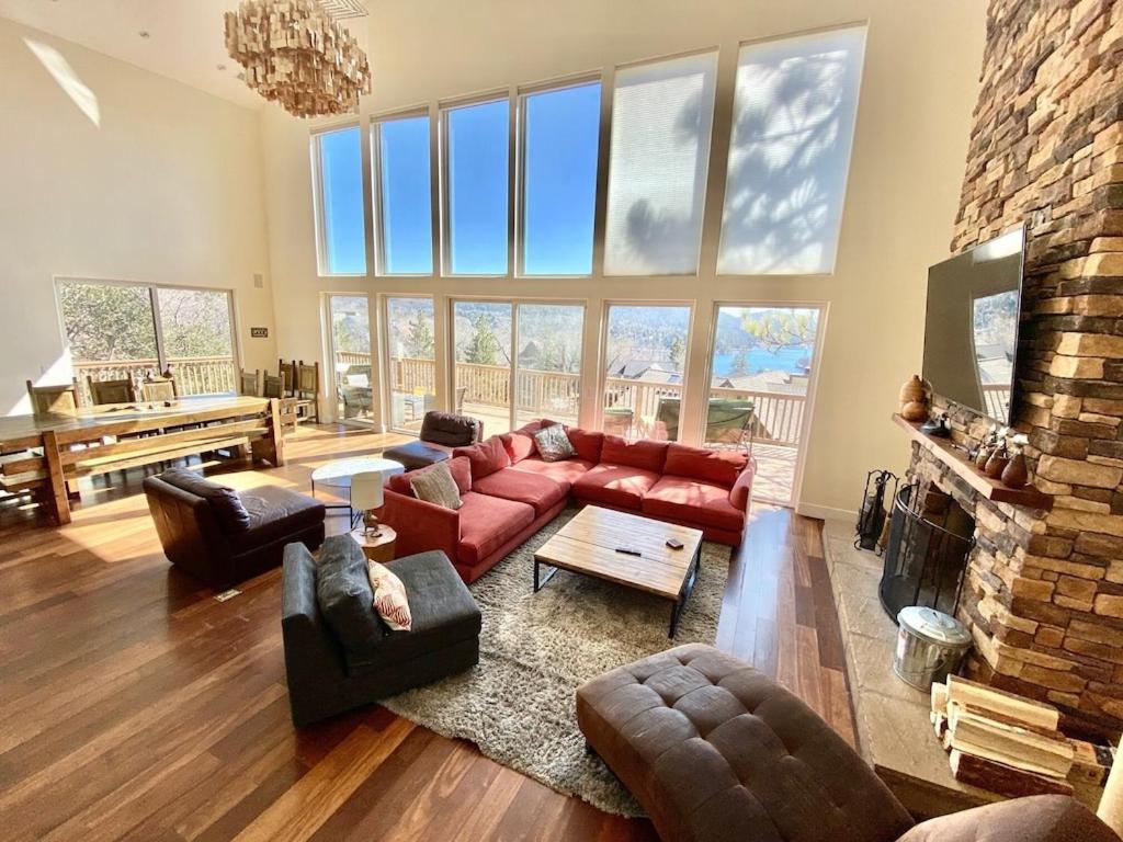 a living room with a red couch and a fireplace at Modern 6 bedroom retreat, stunning lake views, close to village! in Lake Arrowhead