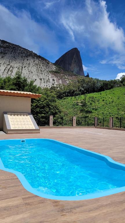 a blue swimming pool with a mountain in the background at Alloggio Peterle in Domingos Martins