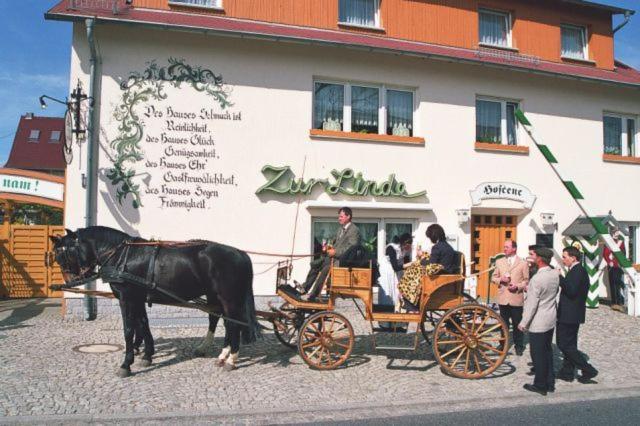 un caballo tirando de un carruaje delante de un edificio en Familienhotel Zur Linde, en Panschwitz-Kuckau