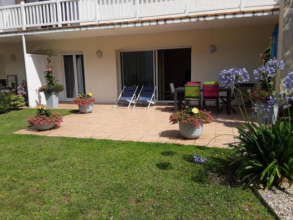 a patio with chairs and flowers in a yard at Appartement Capbreton, 2 pièces, 4 personnes - FR-1-239-872 in Capbreton