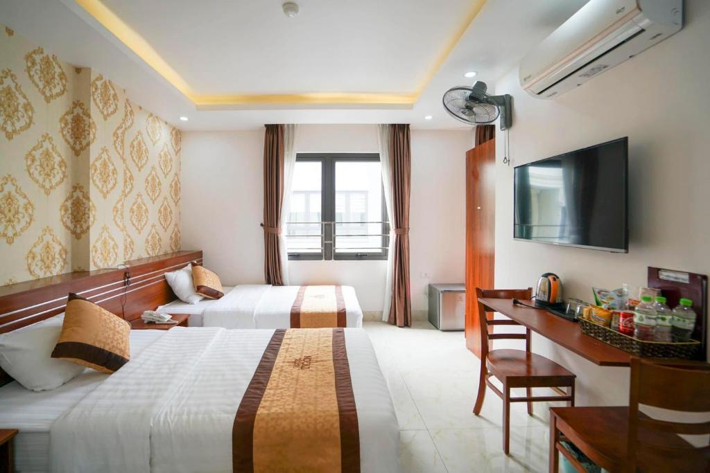 a hotel room with two beds and a television at TiGon Hotel in Ha Long