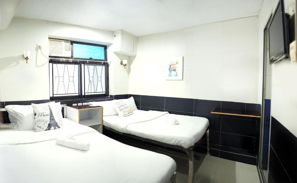Habitación con 2 camas y ventana en Apple Hostel, en Hong Kong
