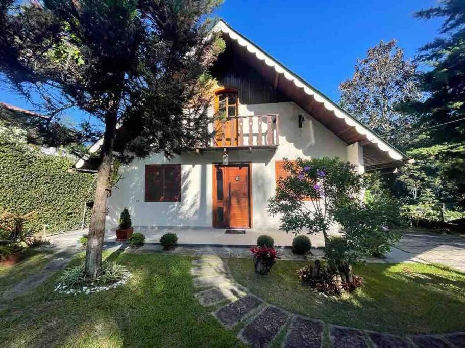 ein weißes Haus mit einem Balkon und einem Hof in der Unterkunft Confortável Chalet na Serra proximo ao Centro in Nova Friburgo