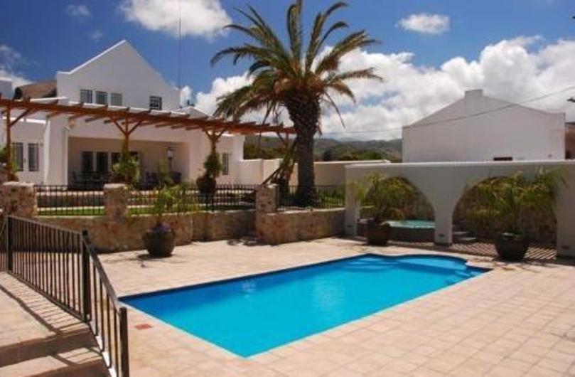 a swimming pool in front of a house at Nautilus Guest House in Hermanus