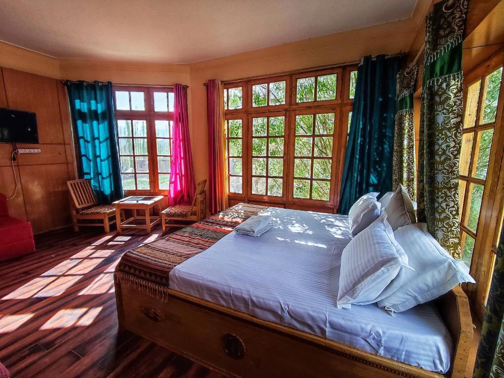 a bedroom with a bed in a room with windows at Snow Lion Ladakh in Leh