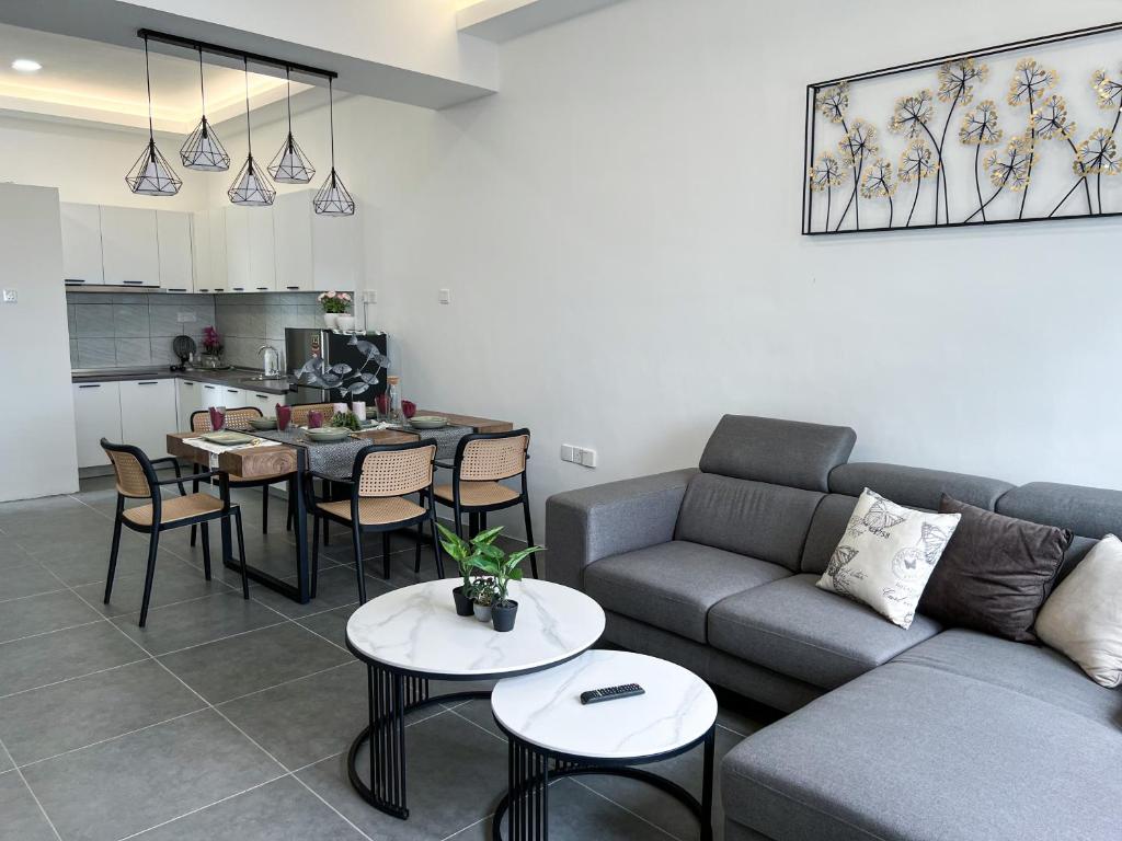 Ins2 Langkawi Apartment Kuah في كواه: غرفة معيشة مع أريكة وطاولات ومطبخ
