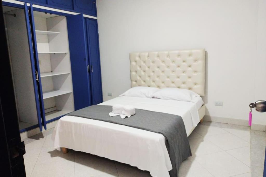 1 dormitorio con cama blanca y armario azul en Apartamento céntrico, cómodo y completamente privado en Cali, en Cali