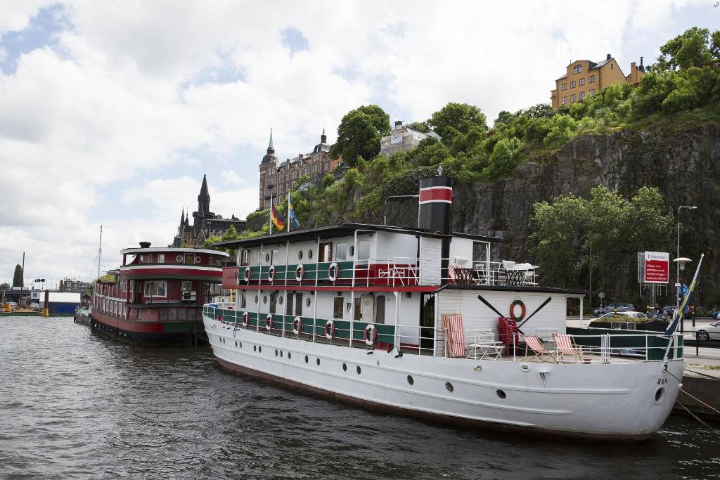 two boats are docked in the water near a city at Den Röda Båten in Stockholm