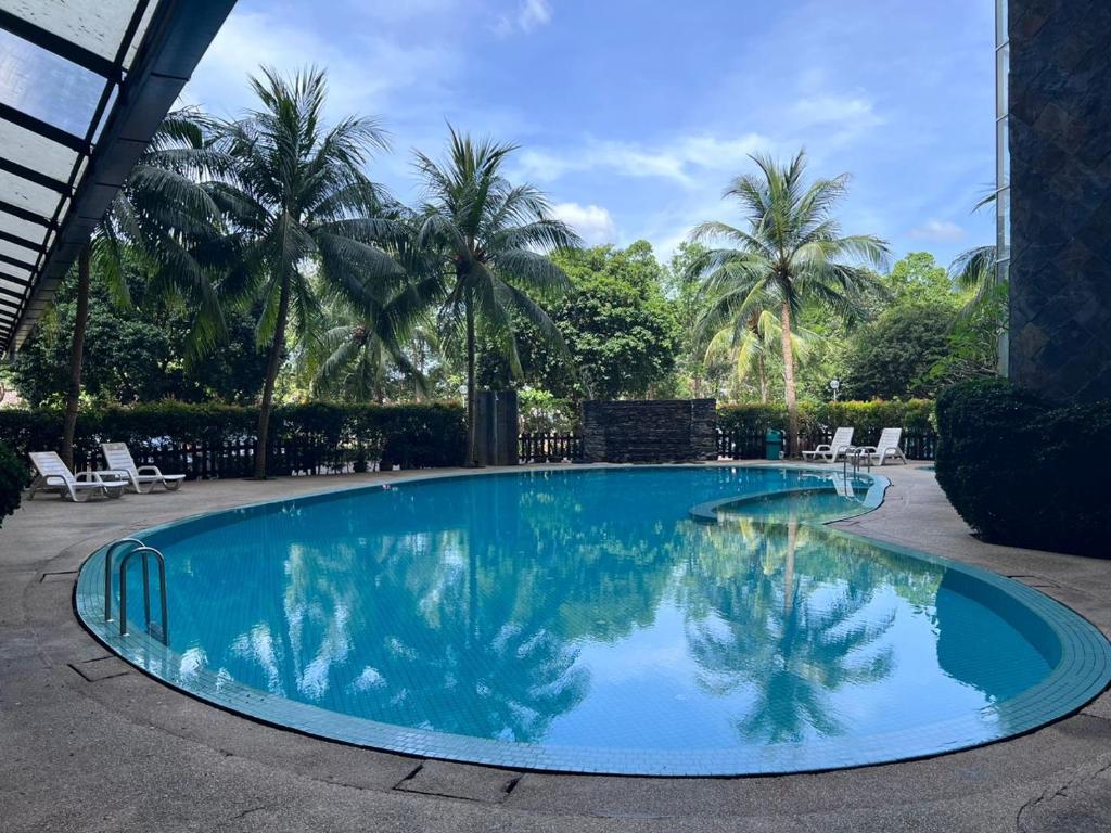 a blue swimming pool with palm trees in the background at RUMAH SINGGAH APARTMENT in Kuah