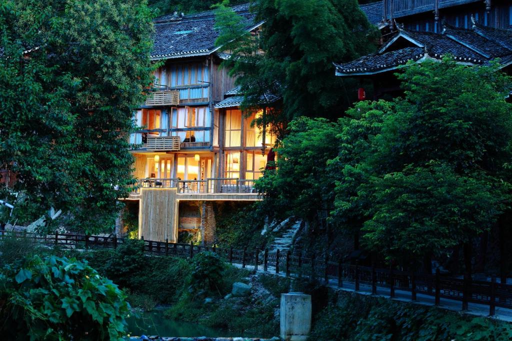 黎平的住宿－侗賞藝術主題酒店，前面有一条河流的大房子