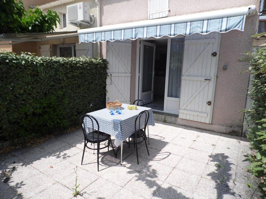 - une table et des chaises sur une terrasse en face d'une maison dans l'établissement Maison avec Terrasse et Piscine, Climatisation, Parking Privé, 34340 Marseillan - FR-1-326-660, à Marseillan