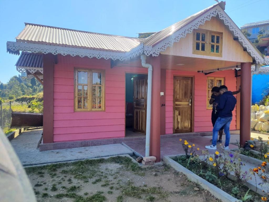 - un couple debout devant une maison rose dans l'établissement Chewa Homestay, à Mangpu