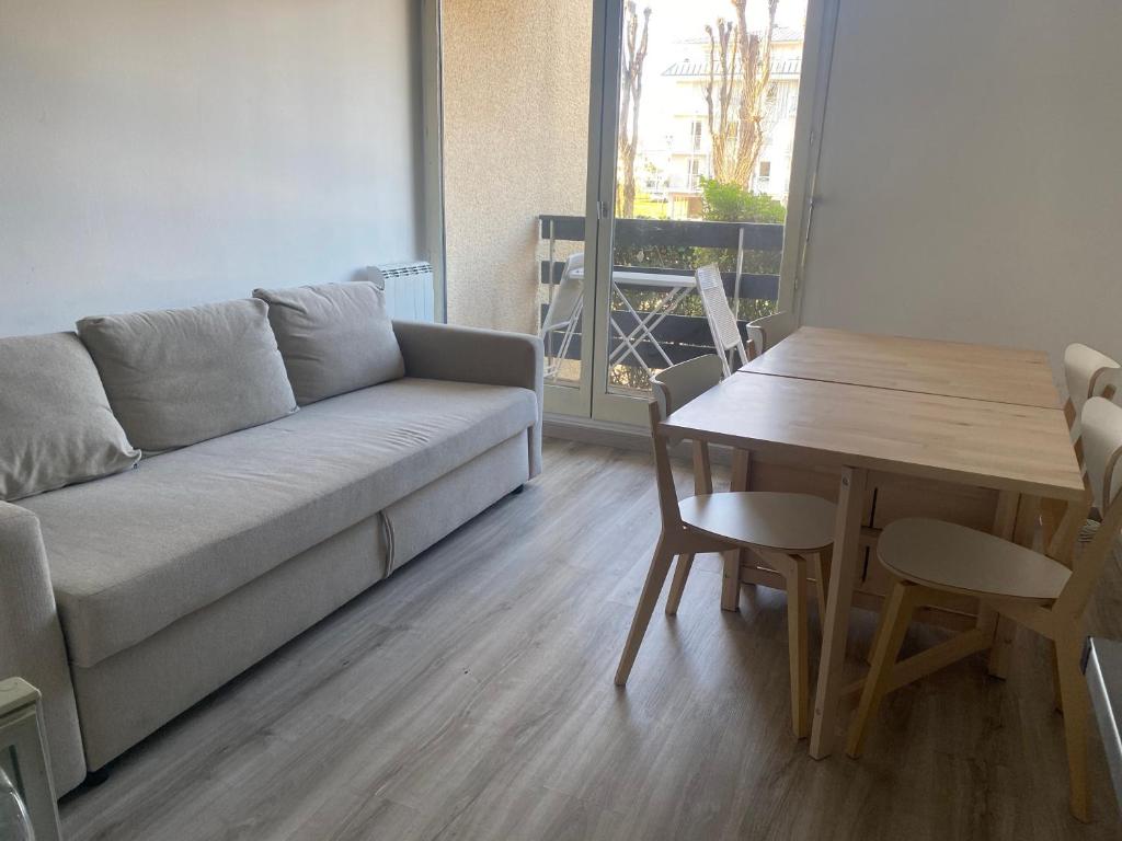 salon z kanapą i stołem w obiekcie Appartement entier en résidence, fonctionnel et confortable w mieście Cabourg