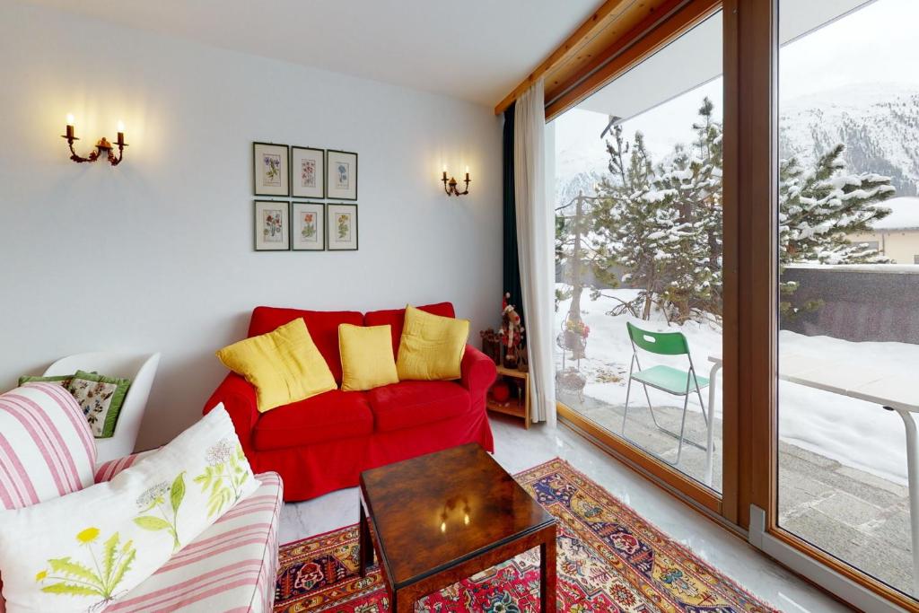 a living room with a red couch and a sliding glass door at Apartment Sur Puoz 2A in Samedan