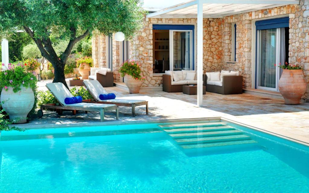 a swimming pool in a yard with chairs and a house at Corfu Luxury Villas in Barbati