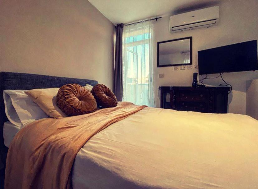 1 dormitorio con 1 cama grande y TV en la pared en Malta Suites en Senglea
