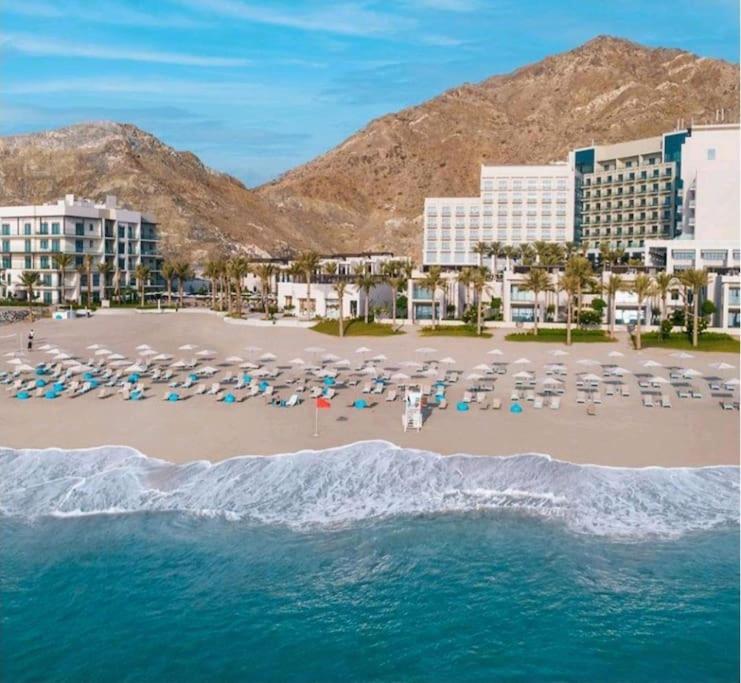 uma vista para uma praia com guarda-sóis e cadeiras em Address Beach Resort Fujairah Apartment 2 Bed Rooms and Small Bed Room - Ground Floor 3011 em Al Aqah