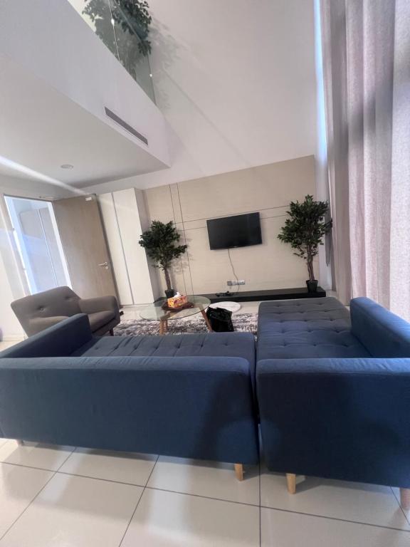 Il comprend un salon doté de canapés bleus et d'une télévision à écran plat. dans l'établissement 3 Rooms family duplex, à Kuala Lumpur