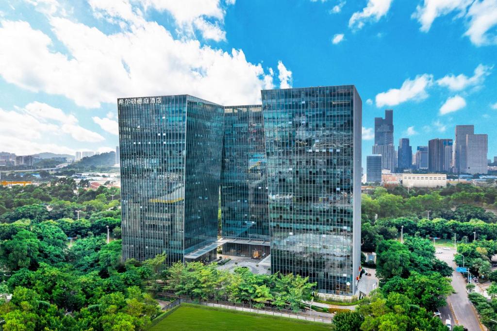 un edificio di alto vetro con una città sullo sfondo di Home2 Suites by Hilton Shenzhen Nanshan Science & Technology Park a Shenzhen