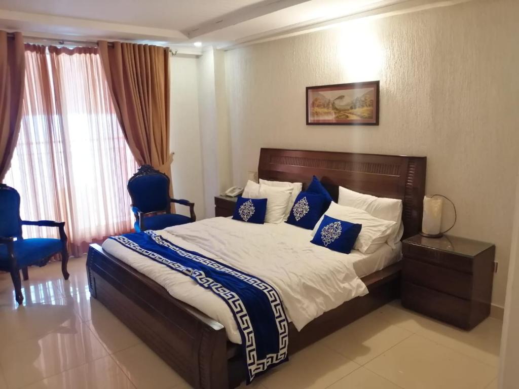 a bedroom with a large bed with blue and white pillows at Gold Suite 402 Bhurban in Murree