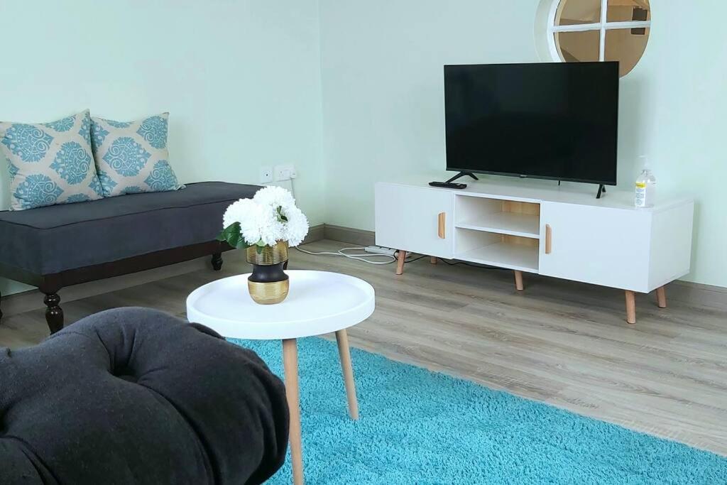 a living room with a tv and a table at Modern &homely guest suite w/free parking in Karen in Nairobi
