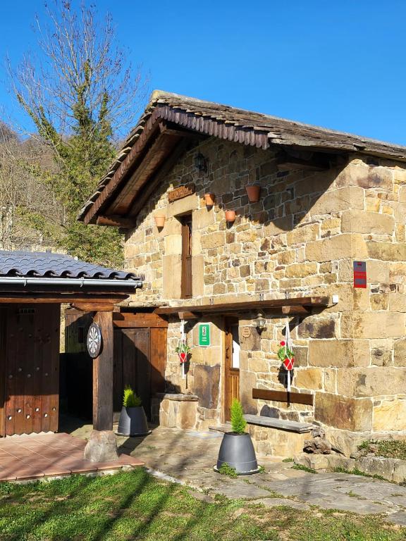 un edificio de piedra con porche y puerta en Cabaña Pasiega La Quemada, en San Pedro del Romeral