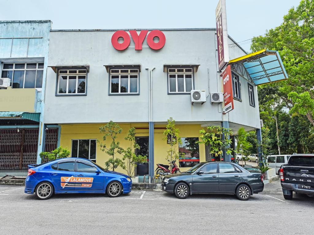 Super OYO 44036 Hotel De Perdana Hill في باتو باهات: سيارتين متوقفتين في موقف للسيارات أمام متجر
