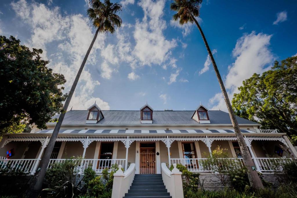 una casa bianca con palme di fronte di De Oude Pastorie a Swellendam