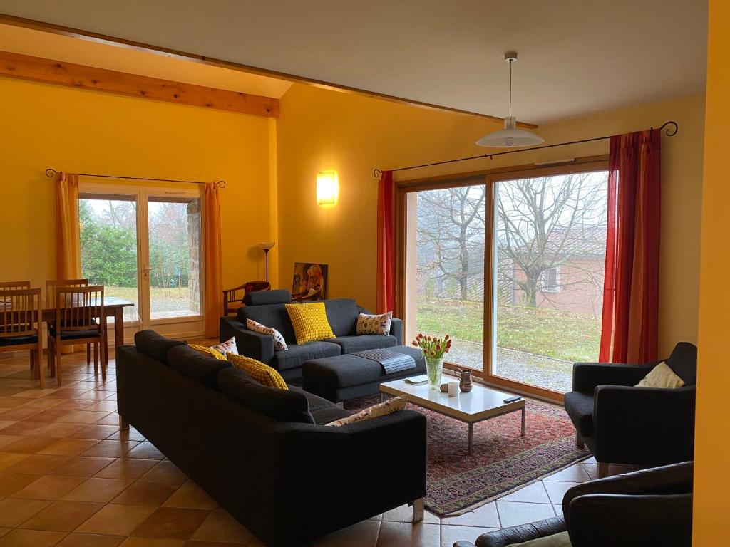 a living room with couches and a table and a large window at La Peyreyre in Jaujac