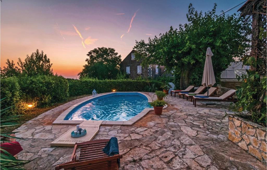 a swimming pool in a backyard with chairs and an umbrella at Nice Home In Nerezisca With 3 Bedrooms, Wifi And Outdoor Swimming Pool in Nerežišće