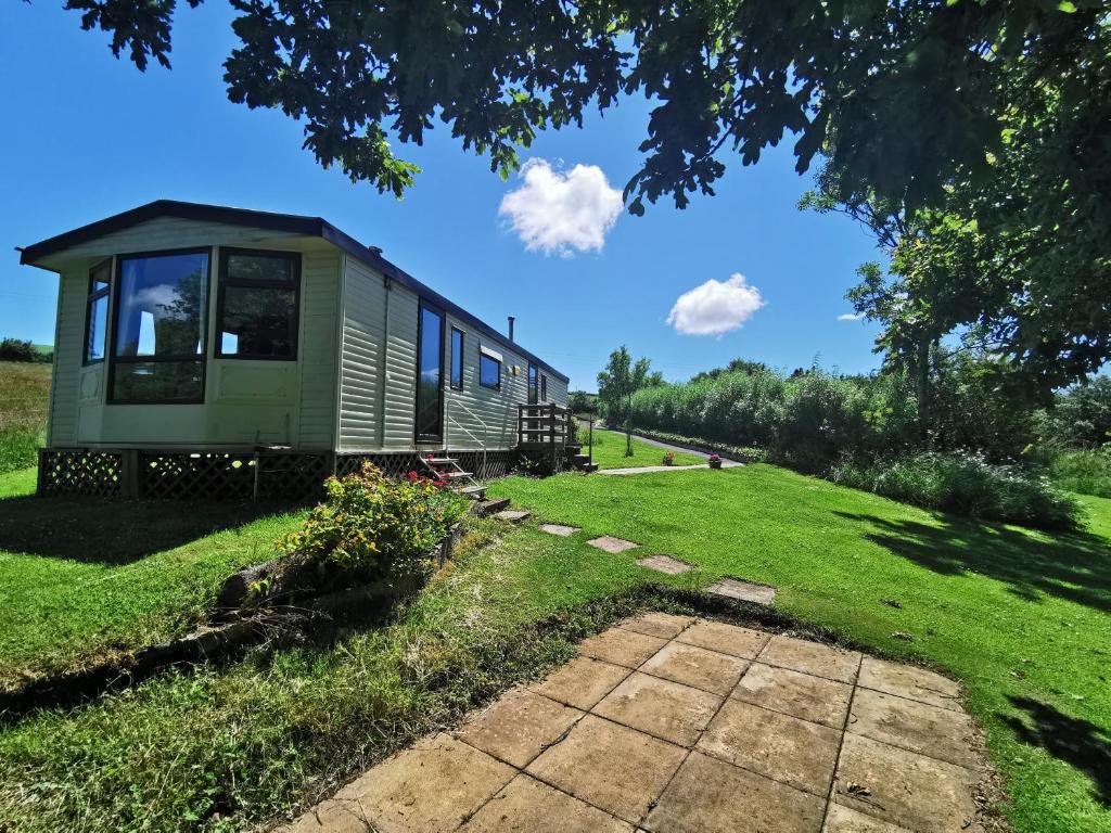 a green tiny house sitting on top of a lush green field at Secluded Farmland Retreat - Valley View in Totnes