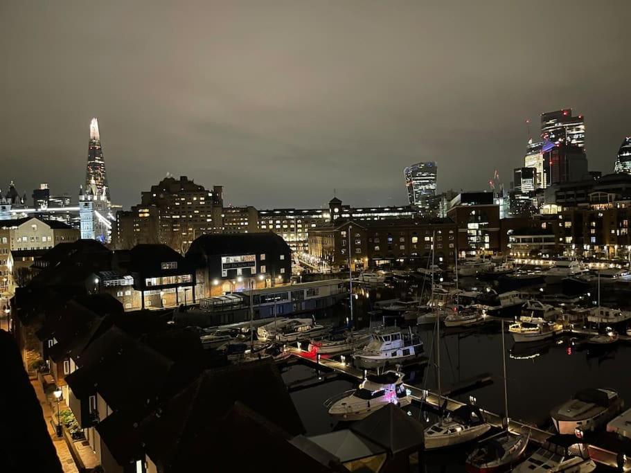 eine Stadt in der Nacht mit Booten in einem Hafen in der Unterkunft Stylish flat next to Tower of London and SKD marina in London
