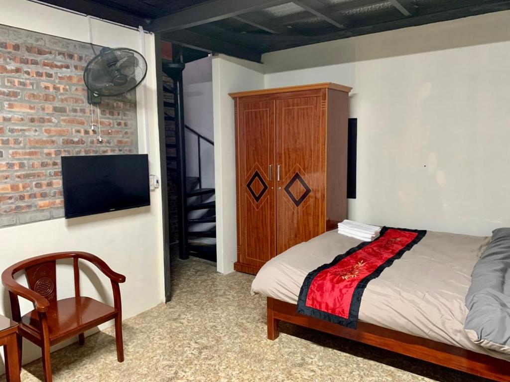 Schlafzimmer mit einem Bett, einem TV und einem Stuhl in der Unterkunft Green Sapa Homestay in Sa Pa