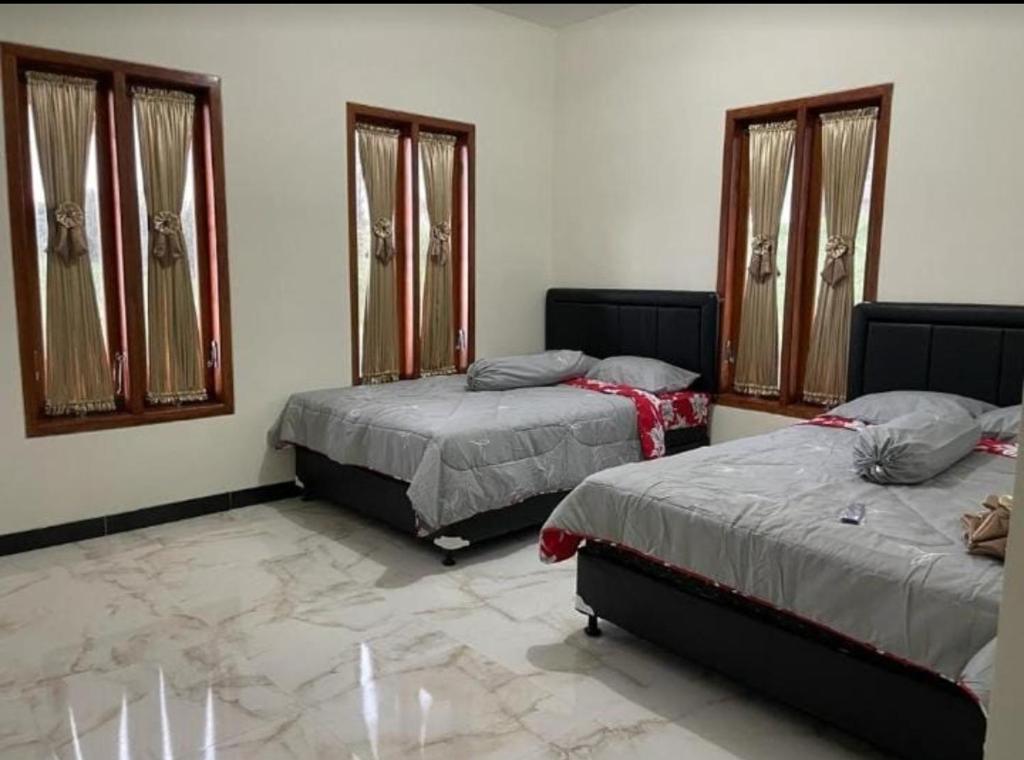 a bedroom with two beds and two windows at Bromo Seruni Astungkara Homestay in Probolinggo