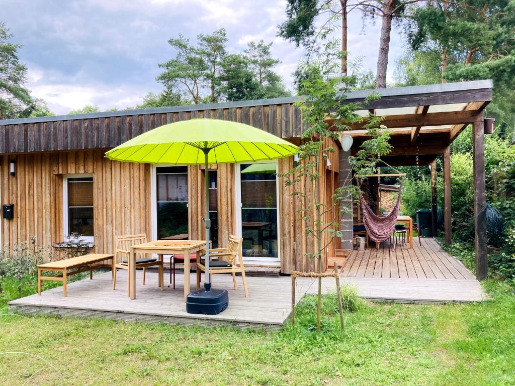 een houten terras met een tafel en een gele paraplu bij Bungalow 314 in Joachimsthal
