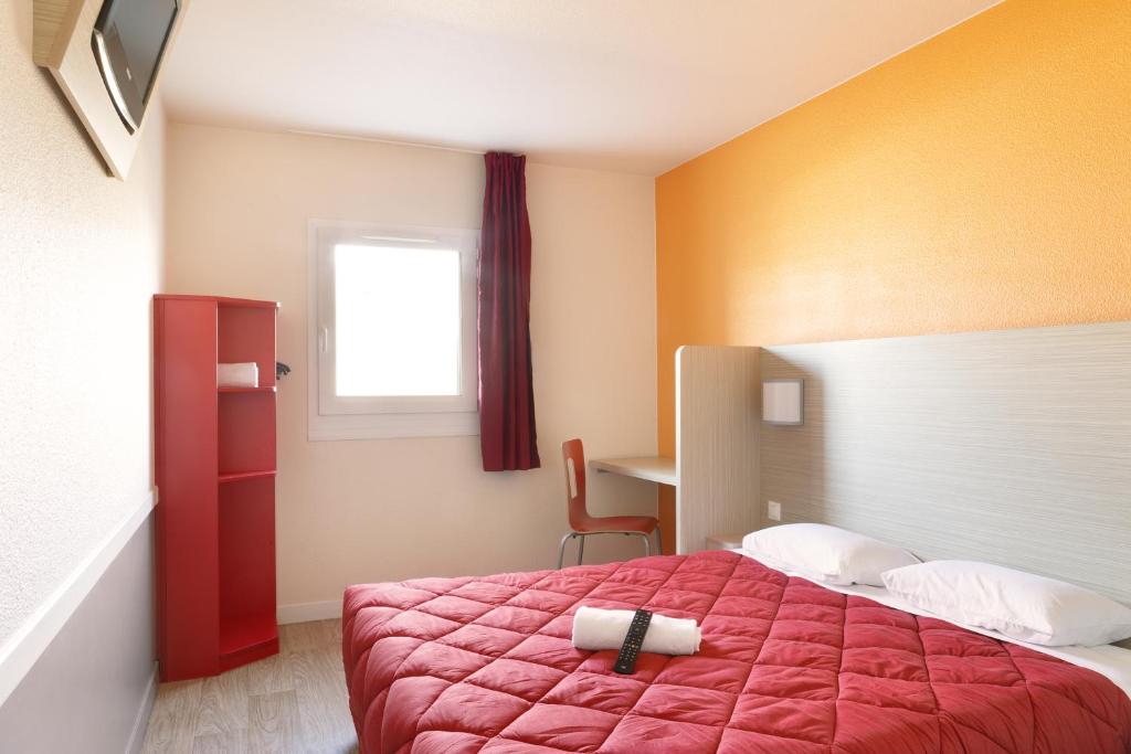 a bedroom with a red bed and a window at Premiere Classe Maubeuge in Feignies