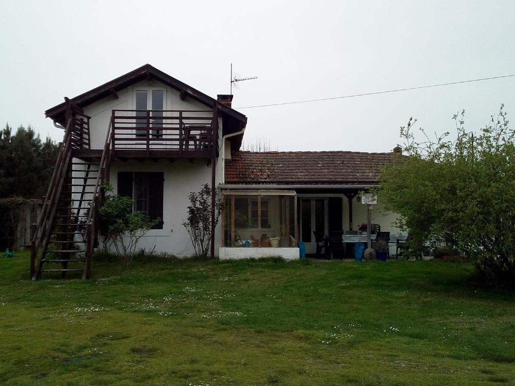 una pequeña casa blanca con porche y escalera en Pedro's garden, en Pontenx-les-Forges